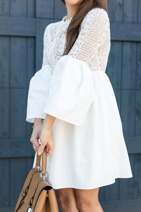 Amy Havins wears a white bell sleeve mini lace dress with stuart weitzman heels.
