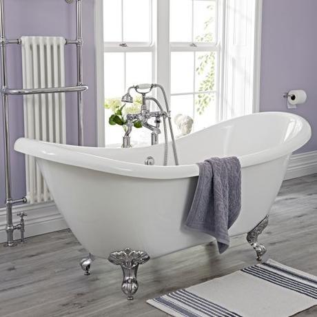 Freestanding bath in a lilac bathroom with a white towel rail