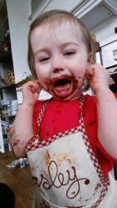 paisley helping mom bake at Love Gets Sweeter with chocolate face
