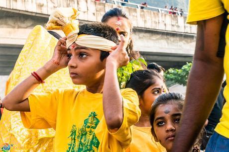 Young boy adjusts his head dress for Thaipusam 2017
