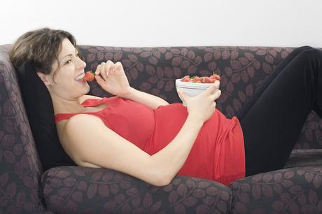 pregnant woman lying down eating strawberries