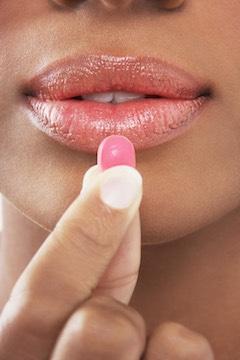 holding vitamin c tablet to mouth