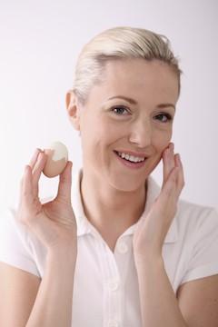 woman holding egg and touching face