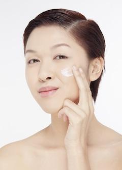 woman smoothing vitamin c cream on face