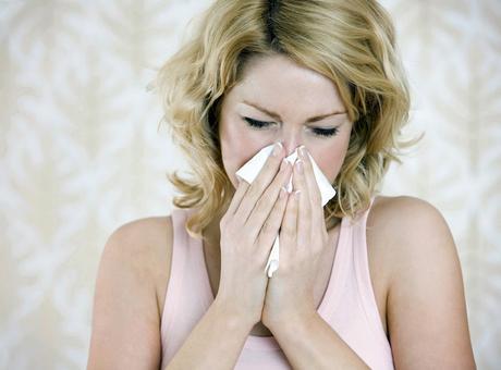 woman with a cold sneezing into tissue