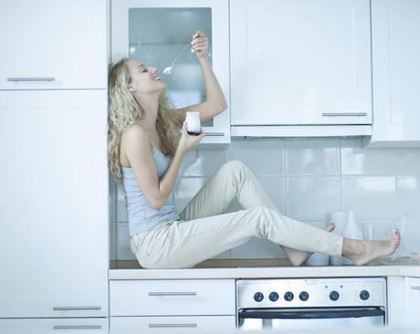 woman eating probiotic yogurt in kitchen