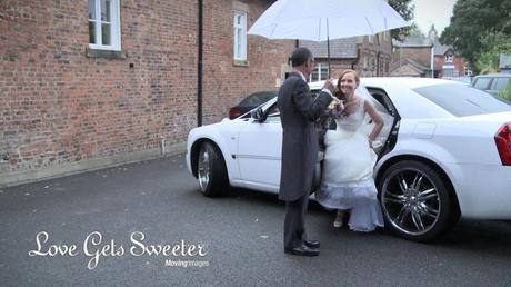 dad helps daughter get out of the bentley wedding car holding an umbrella in the rain
