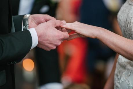 groom placing ring on brides finger 