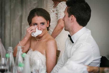 bride looking at groom wiping her eye 