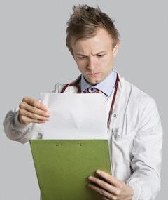 Male doctor reading medical records over gray background