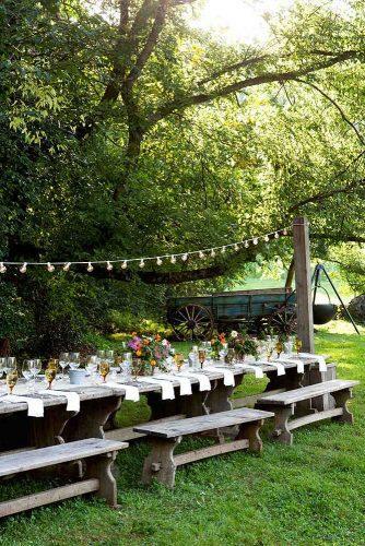 country wedding wedding reception on a green meadow wooden tables and benches field flowers on a table beall + thomas photography