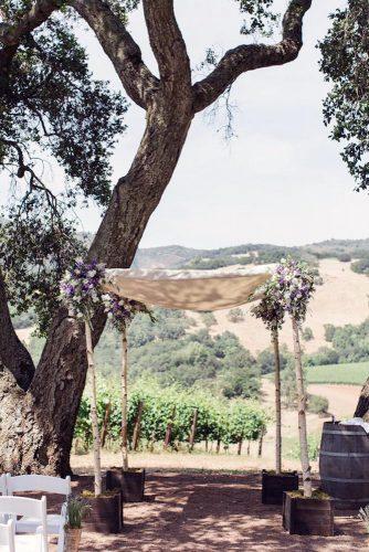 rustic backyard wedding arch of birch wood decorated with flowers and cloth cly by matthew