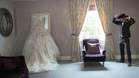 Ian Stuart blush layered wedding dress hanging up on a full length mirror for the wedding video in West Yorkshire