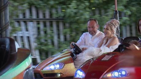 bride and groom having a go on the dodgem bumper cars during their fairground wedding reception in drighlington