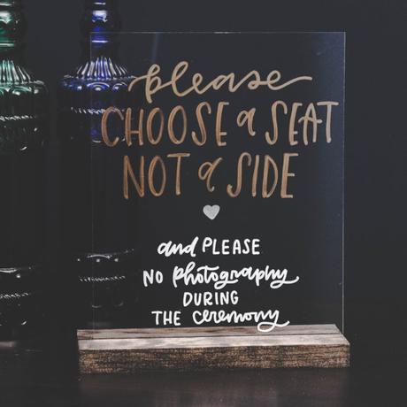 acrylic wedding sign saying choose a seat not a side and no photography please