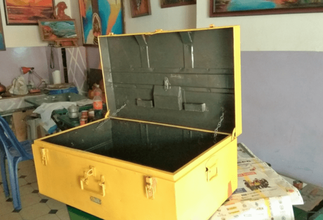 The box painted yellow with the handle, hinges, locks and latch painted orange