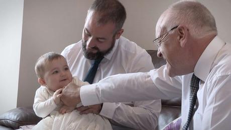 dad and grandad getting giggles off baby charlotte before her christening