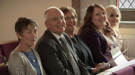 grandparents and aunties laughing sat in the pews at Rhyl church during a christening