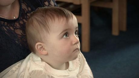 baby girl during christening looking very serious on the video