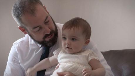 Charlotte ready in her Next christening gown sat on her Dad's knee
