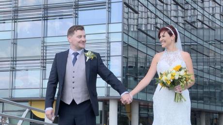 the bride and groom hold hands and look at each other for their wedding photographs at Media City Manchester