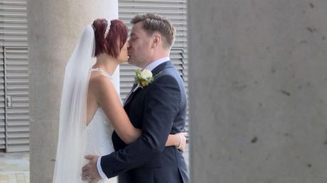 The bride and groom enjoy a kiss for the photographer and videographer outside media city