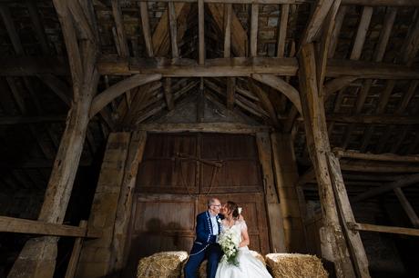Bride and groom on haybeale in barn at East Riddlesden Hall