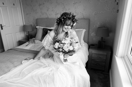 Tux and tales photography York bride sitting on bed with flowers