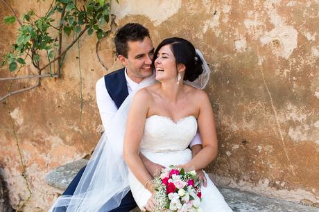 Couple laugh in front of Tuscan wall