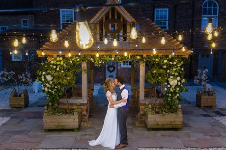 Bride and groom kiss under festoon lights york wedding photography
