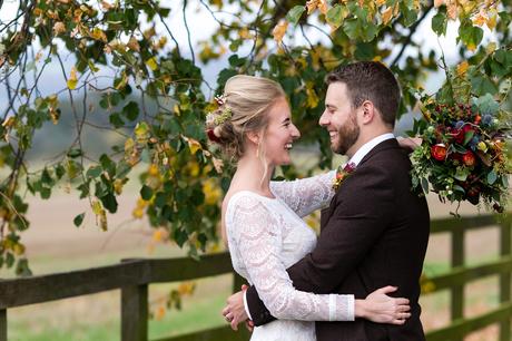 Bride and groom kiss and cuddle under autumn tree at york wedding