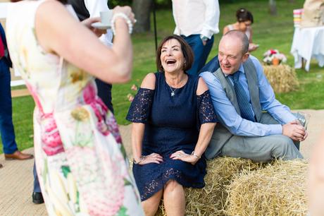 Guest laughing at york wedding sitting on haybale