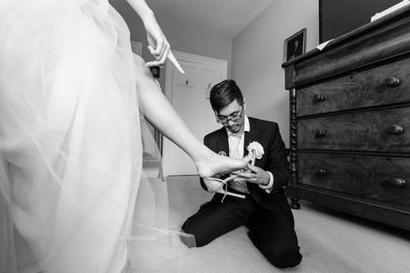 Bride points to shoe whilst groomsman buckles it funny wedding photos york