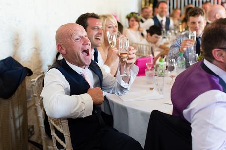 Guests laugh during speeches at wedding