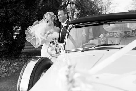 Bride and groom laugh next to vintage car a york wedding