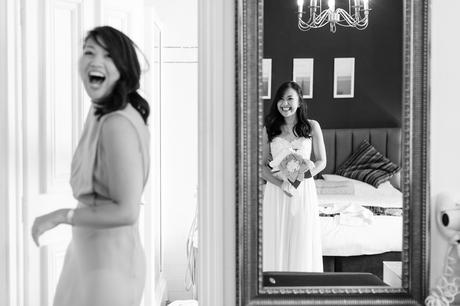 Bride checking her reflection in mirror whilst sister laughs best york wedding photography