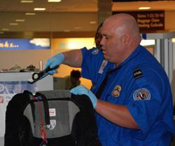 A TSA officer screens a piece of luggage.