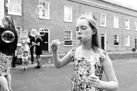 Little girl pouts in front of bubbles at quirky wedding in London