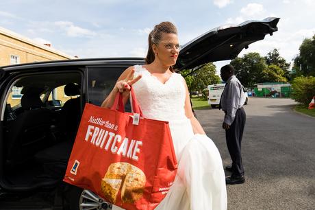 Bride giving peace symbol and holding Aldi bag at London wedding