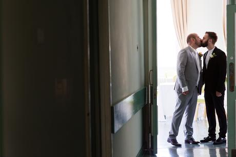 Grooms kissing before ceremony at same sex wedding
