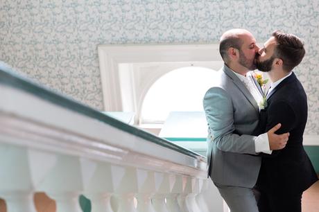 A fun Yorkshire Wedding grooms kissing in front of beautiful patterned wallpaper