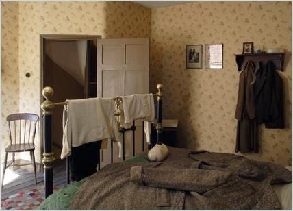 a view of the 1930s house bedroom at the birmingham back to backs showing the bed and bedstead with a coat spread over it for additional warmth