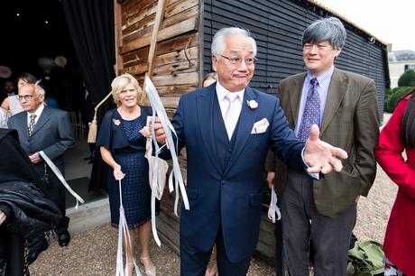 Father making cilly face as he hands out ribbon wands Preston Court Wedding Photography