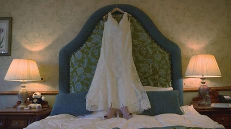 A brides dress hangs waiting for its bride in a bedroom suite at Nunsmere Hall
