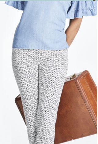 A travel briefcase in tan leather styled with pastel blue top and woven/knitted trousers. Courtesy: Nic+Zoe