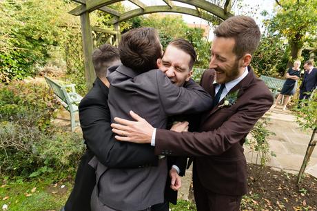 Groomsmen hug groom making him laugh Sandburn Hall Wedding Photography