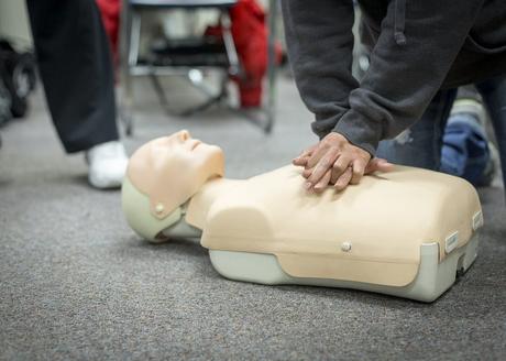 A person taking a CPR class practices on a mannequin.