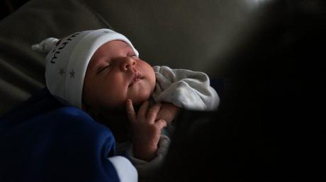 a close up of a sleeping baby in the arms of her uncle with natural light showing off her little face and features as she sleeps in Newark Nottinghamshire