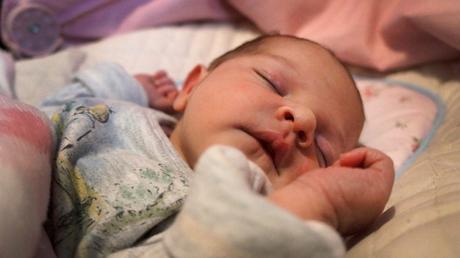 A newborn baby girl sleeps in her bouncy chair unaware she is being photographed