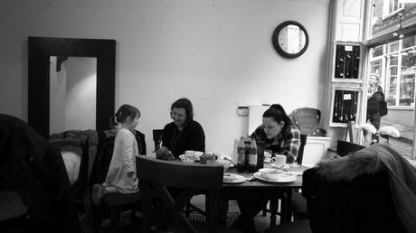 a grandma, aunt and niece sit around a cafe table after their lunch talking to a newborn baby in Lincoln